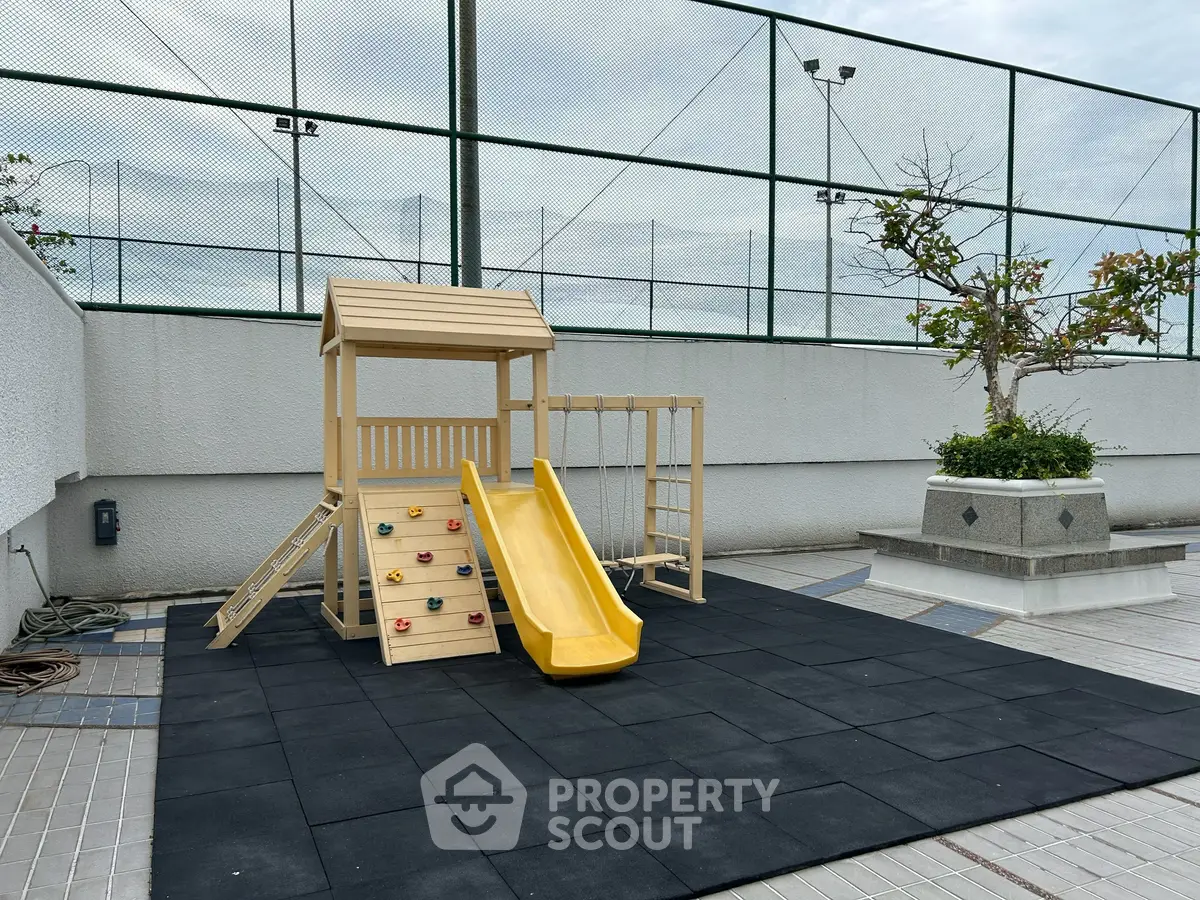 Modern outdoor playground area with slide and climbing wall in residential complex.