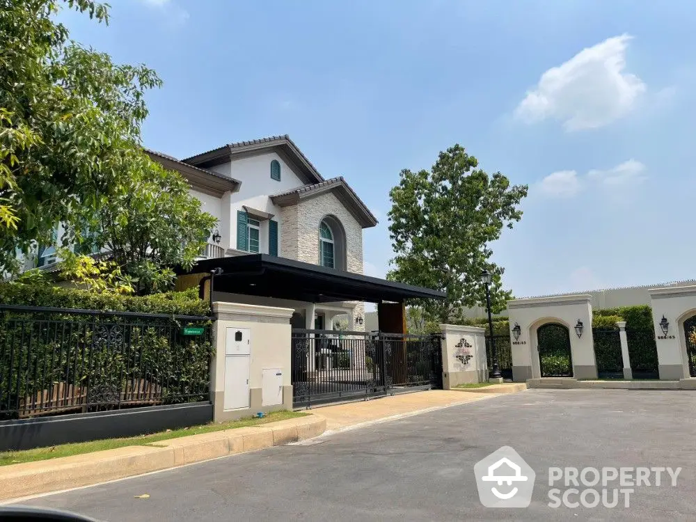 Elegant two-story home with a classic design, featuring a lush garden and secure gated entrance, showcasing a spacious driveway and inviting facade.