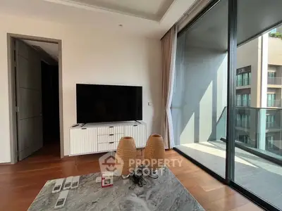 Modern living room with large glass doors leading to a balcony, featuring a sleek TV stand and stylish decor.