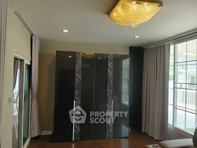 Modern living room with elegant chandelier and large wardrobe, featuring floor-to-ceiling windows for natural light.