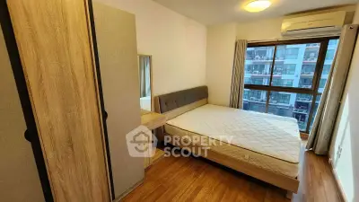 Cozy bedroom with modern furnishings and city view, featuring a comfortable bed and ample storage space.