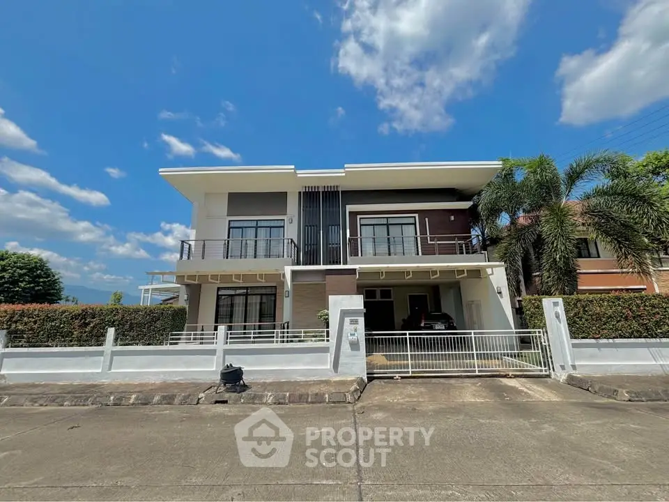 Modern two-story house with sleek design and lush landscaping under a clear blue sky.