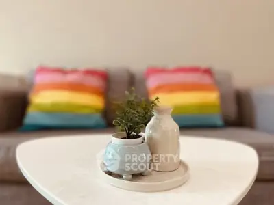Stylish living room with colorful cushions and modern decor on a sleek white table.
