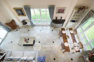Elegant living room with high ceiling, large windows, and stylish decor overlooking a lush garden.
