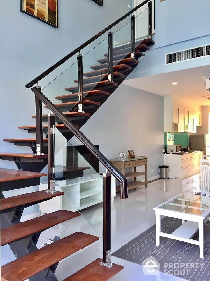 Modern open-plan living area with stylish staircase and sleek kitchen design.