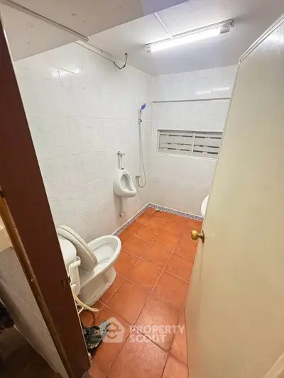Compact bathroom with tiled floor and wall-mounted shower in a real estate property.