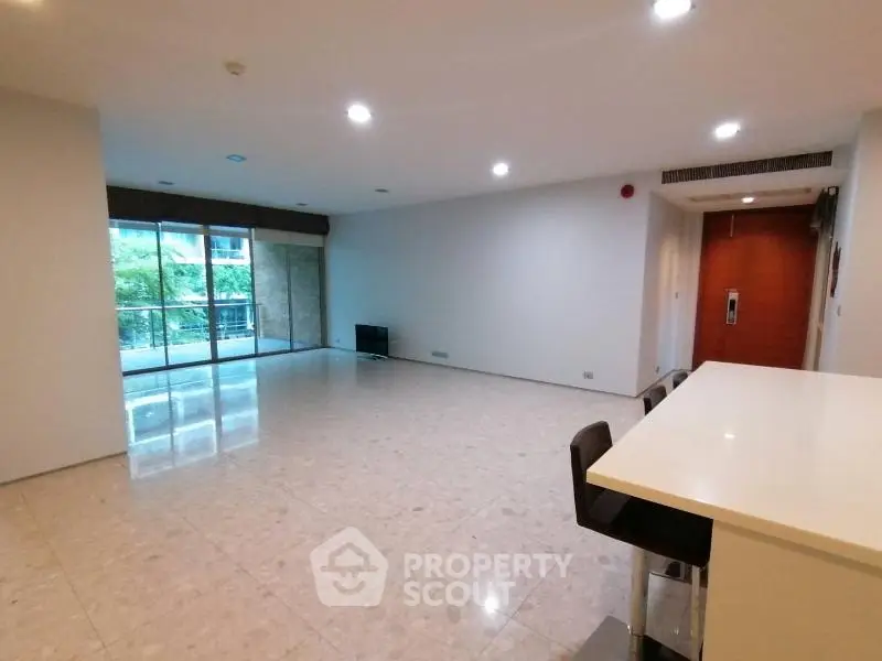 Spacious modern living room with large windows and balcony access in a luxury apartment.