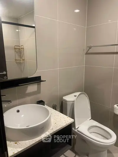 Modern bathroom with sleek fixtures and elegant design, featuring a round basin and contemporary toilet.