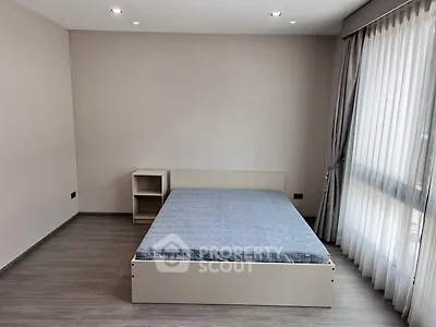 Spacious bedroom with modern bed and large window for natural light.