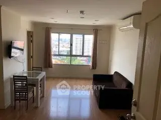 Bright living room with city view, modern furniture, and wall-mounted TV.