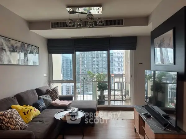Modern living room with large windows and city view, cozy sofa and stylish decor.