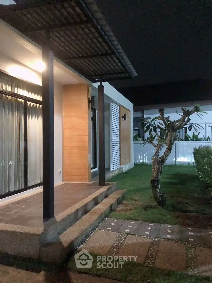 Modern house exterior with stylish patio and garden at night