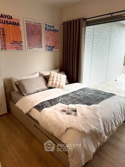 Cozy bedroom with stylish decor and large window offering natural light.
