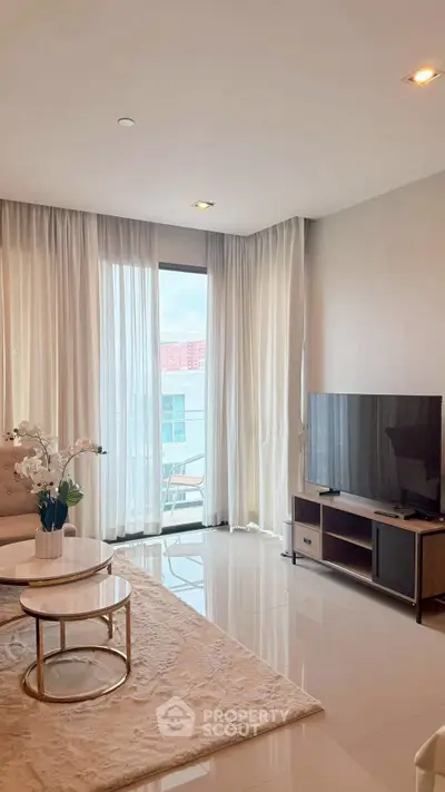 Elegant living room with modern decor, large TV, and floor-to-ceiling windows offering natural light.