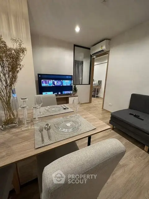 Modern living room with dining area, TV, and air conditioning in stylish apartment.