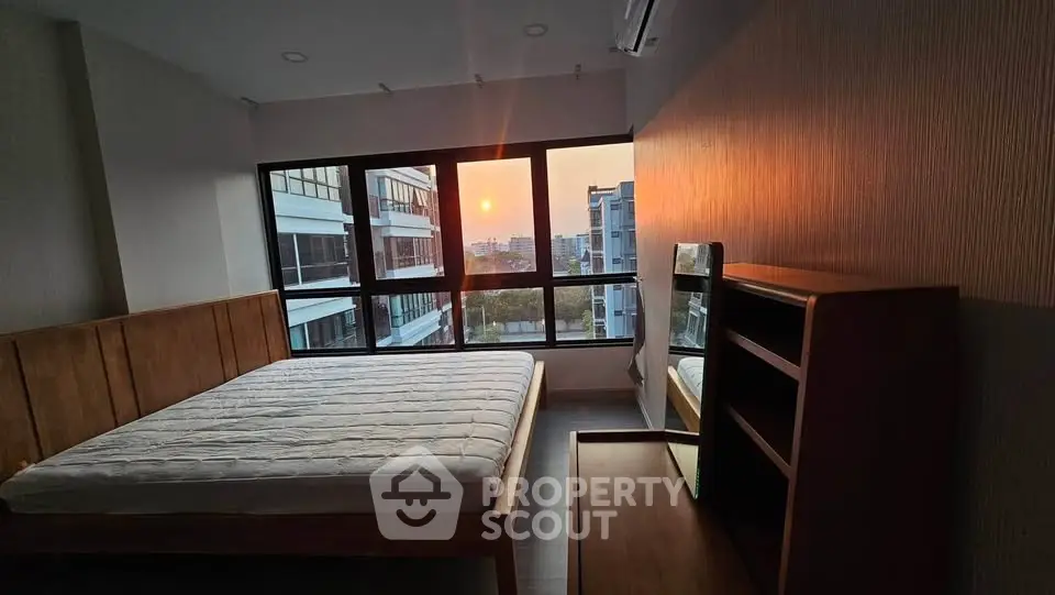Spacious bedroom with large windows offering stunning sunset views in modern apartment.