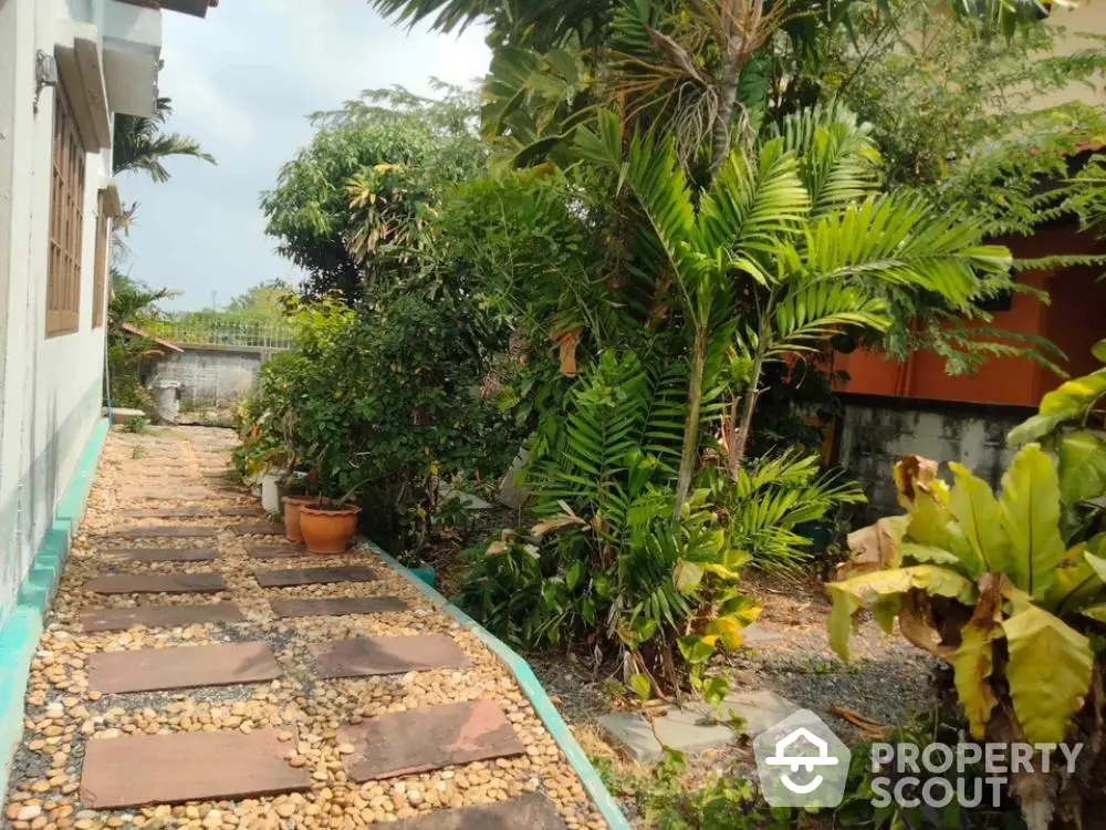 Lush tropical garden pathway in serene residential setting, perfect for nature lovers seeking a tranquil outdoor space.