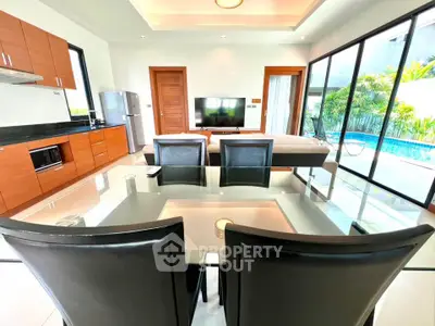 Modern open-plan living room with pool view, sleek kitchen, and elegant dining area in a luxury home.