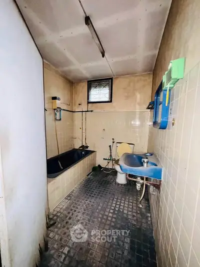Vintage bathroom with classic blue sink and black bathtub, offering a unique renovation opportunity.
