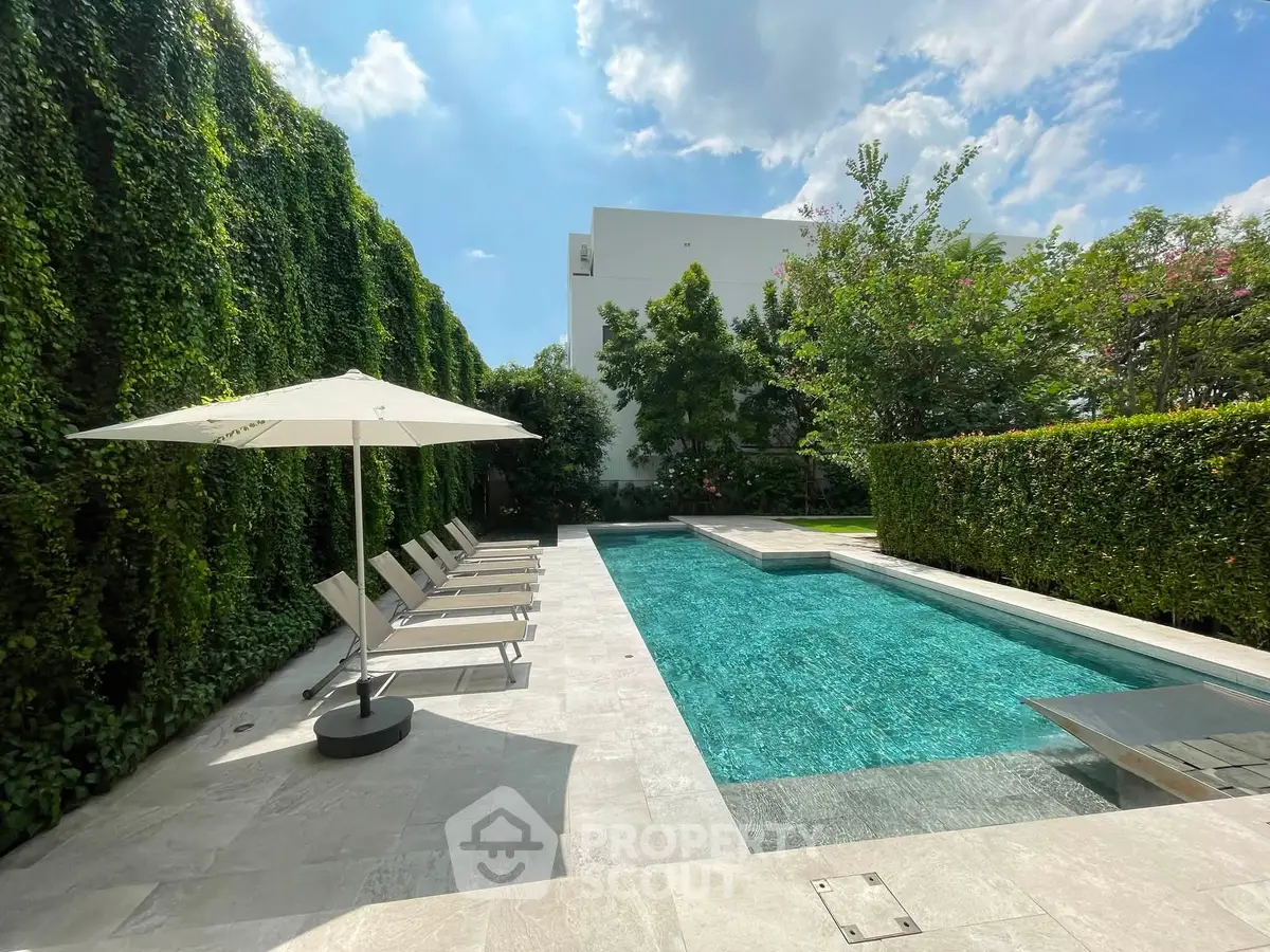 Luxurious private pool with sun loungers and lush greenery, perfect for relaxation and entertainment.