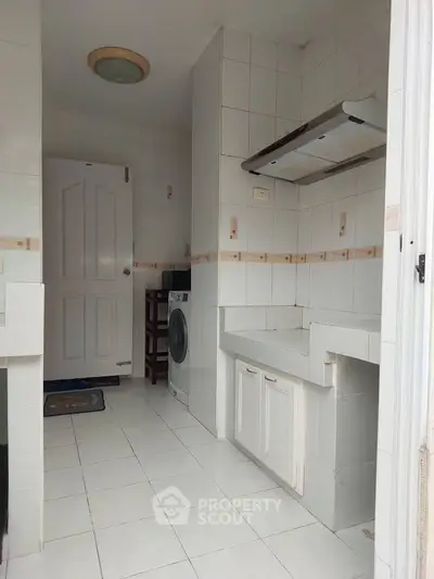 Compact kitchen with washing machine and white cabinetry