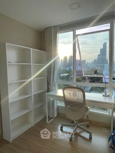 Bright study room with city view, featuring a desk, chair, and bookshelf, ideal for productivity.