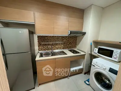 Modern compact kitchen with wooden cabinets, mosaic backsplash, and appliances including fridge and washing machine.