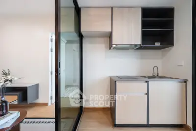 Modern compact kitchen with sleek cabinetry and glass partition in a stylish apartment.