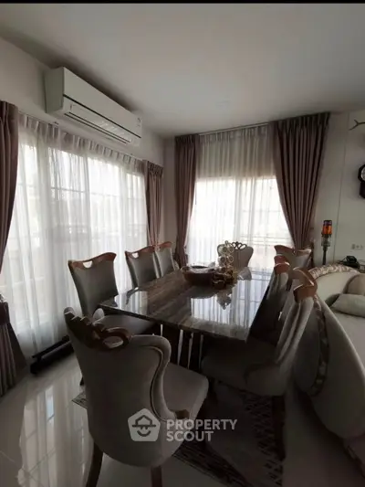 Elegant dining area with marble table and plush chairs in a bright, airy living space.