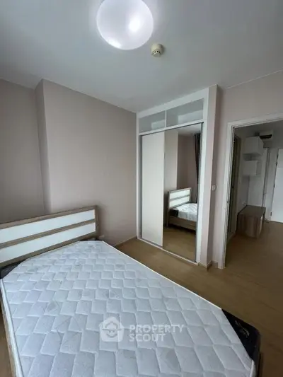 Modern bedroom with minimalist design, featuring a comfortable bed and mirrored wardrobe for ample storage.