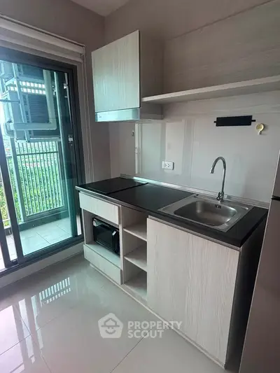 Modern kitchen with sleek cabinetry and balcony access in a stylish apartment.