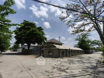 Charming residential building with lush greenery and spacious driveway under a clear blue sky.