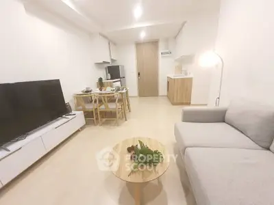 Modern living room with open kitchen, cozy sofa, and stylish decor in a bright apartment.