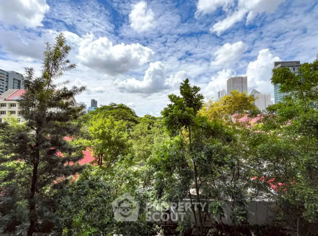Stunning cityscape view with lush greenery and skyline under a vibrant blue sky.