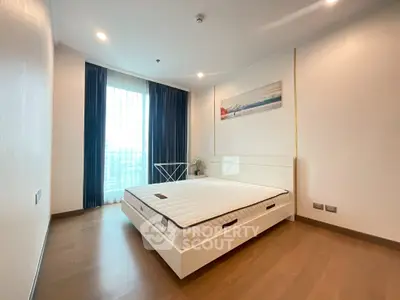 Modern bedroom with large window and stylish decor in a high-rise apartment.