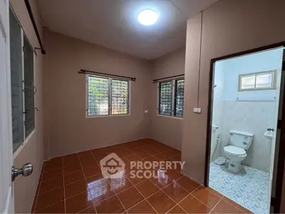 Cozy room with tiled floor and attached bathroom, ideal for compact living.