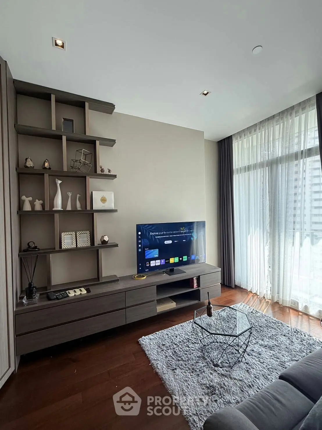 Modern living room with stylish shelving, large TV, and floor-to-ceiling windows for natural light.