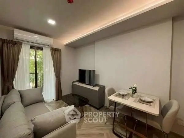 Modern living room with cozy sofa and dining area, featuring a sleek TV setup and natural light.