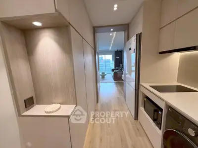 Modern kitchen with sleek appliances and open layout leading to a bright living area with city view.