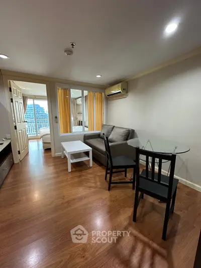 Spacious living room with wooden flooring and modern furniture in a high-rise apartment.