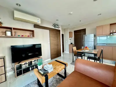 Modern living room with open kitchen, stylish furniture, and natural light.