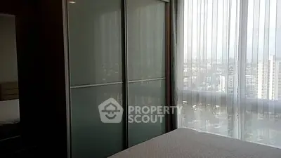 Modern bedroom with city view and large window, featuring sleek sliding closet doors.