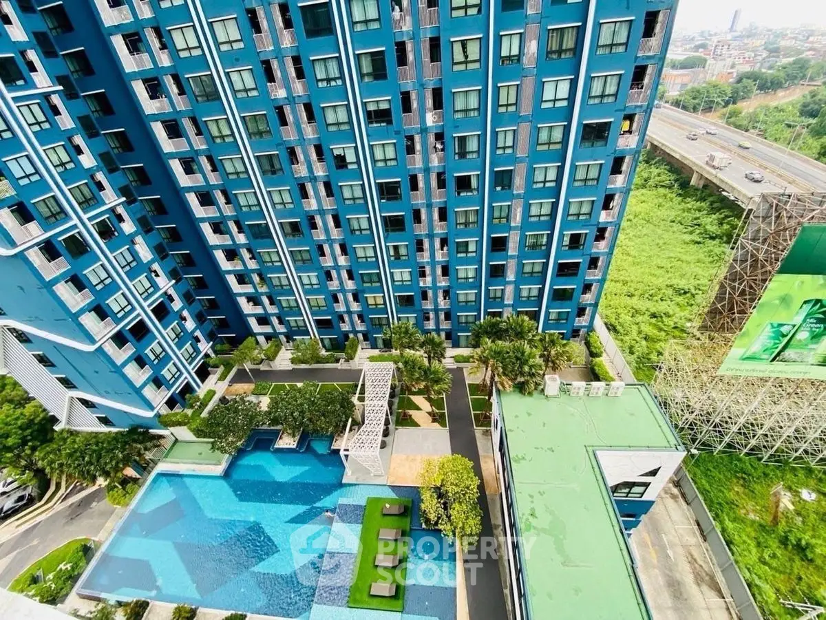 Stunning aerial view of modern blue high-rise with pool and lush greenery