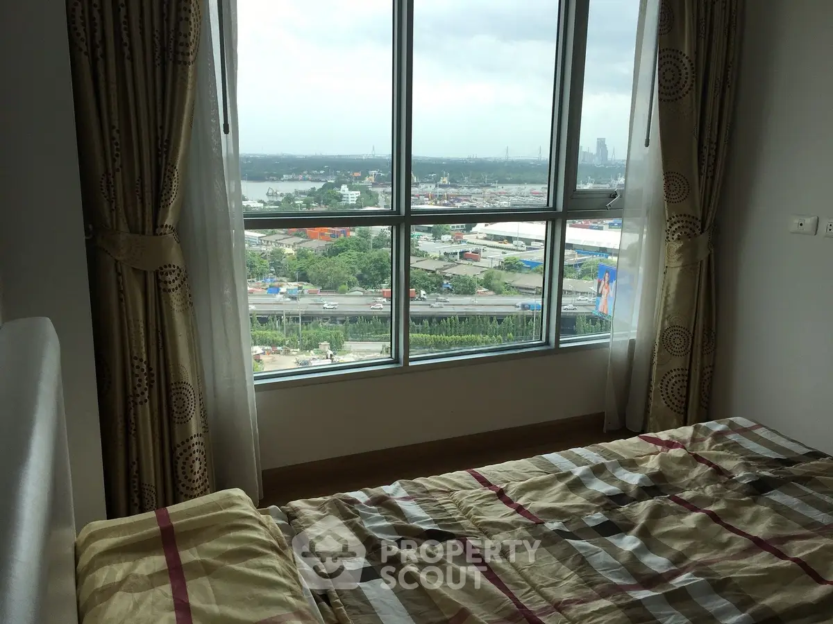 Cozy bedroom with a stunning city view through large windows, perfect for urban living.