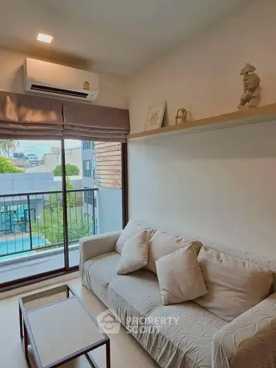 Cozy living room with modern decor and pool view, featuring a comfortable sofa and air conditioning.