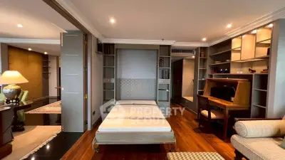 Luxurious living room with elegant wooden flooring and built-in shelving, featuring a cozy workspace and stylish decor.