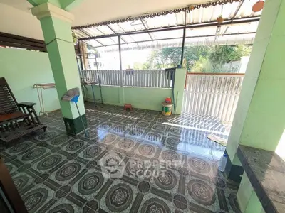 Spacious covered patio with decorative tile flooring and garden view.