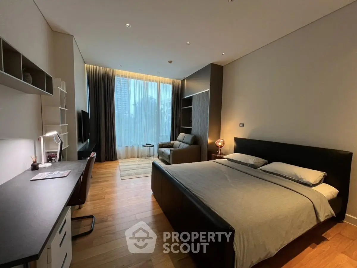 Luxurious bedroom with modern decor and city view, featuring a cozy workspace and elegant furnishings.