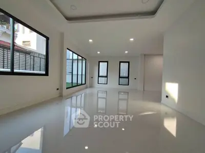 Spacious modern living room with large windows and glossy white flooring