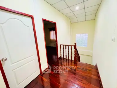 Spacious hallway with wooden flooring and elegant staircase in modern home